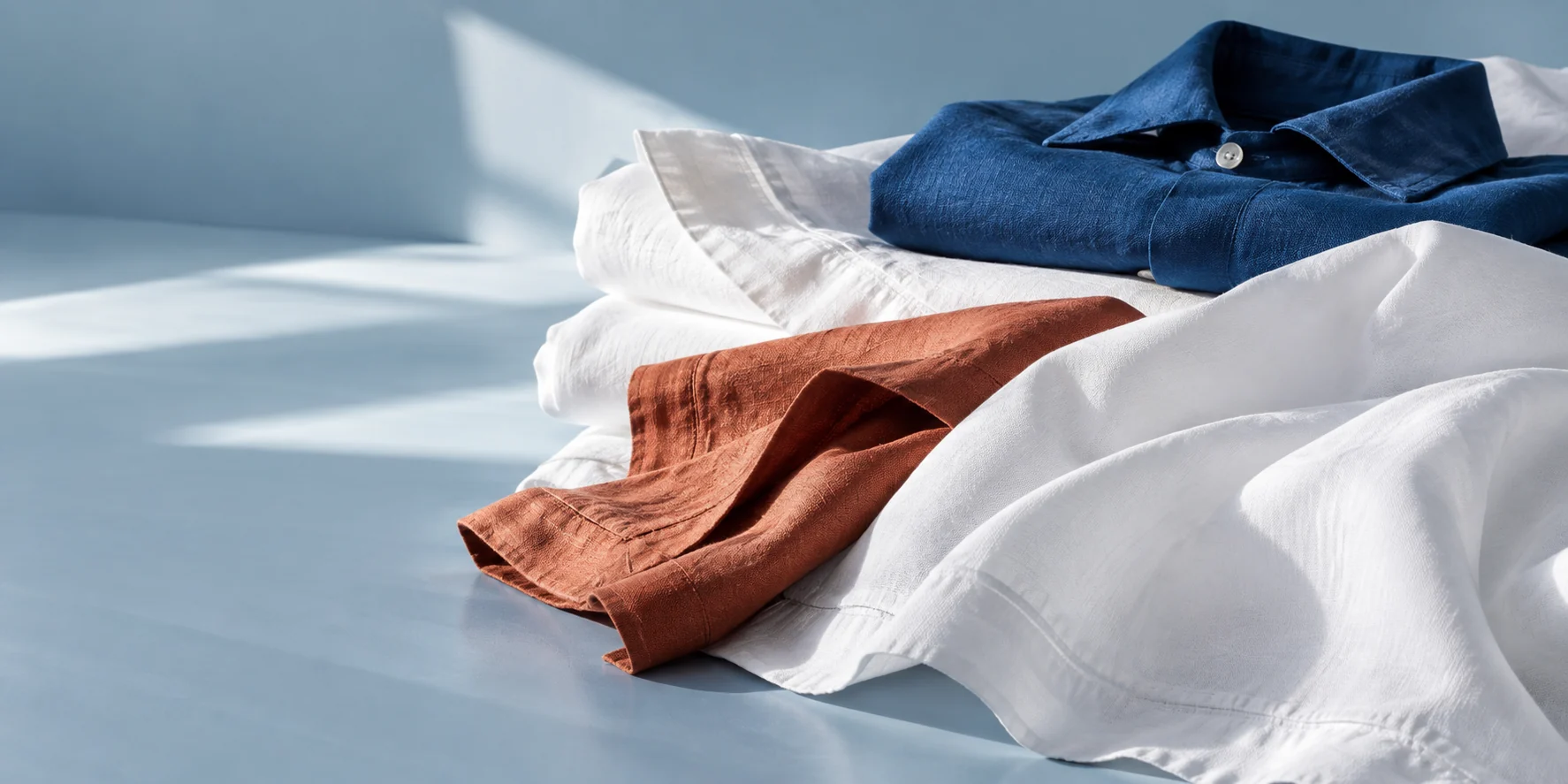 Inszenierte, gefaltete Textilien in Weiss, Blau und Terrakotta